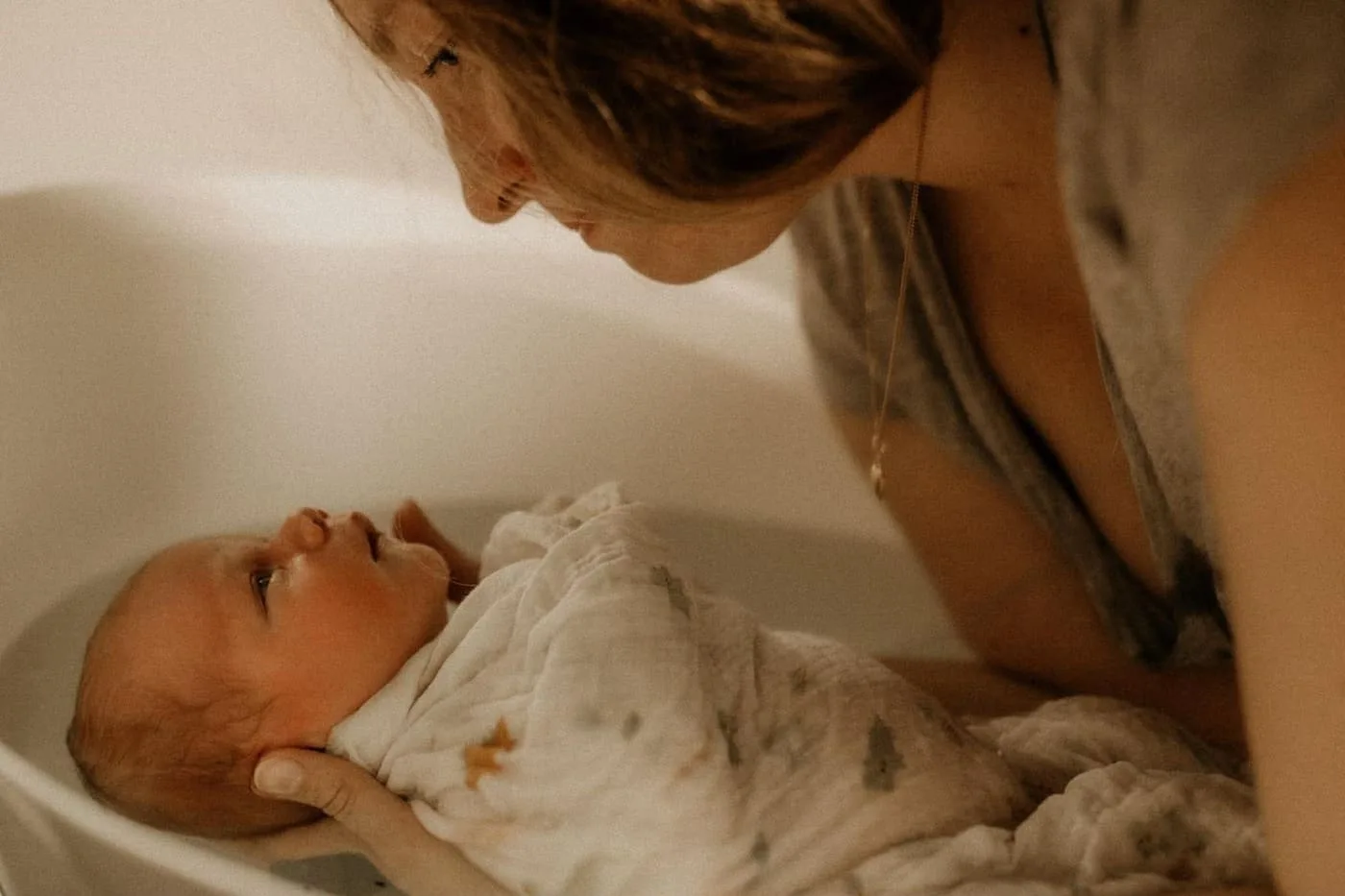 Regard complice entre une mère et son nouveau-né pendant un bain sensoriel, accompagnés par Marine Eloy