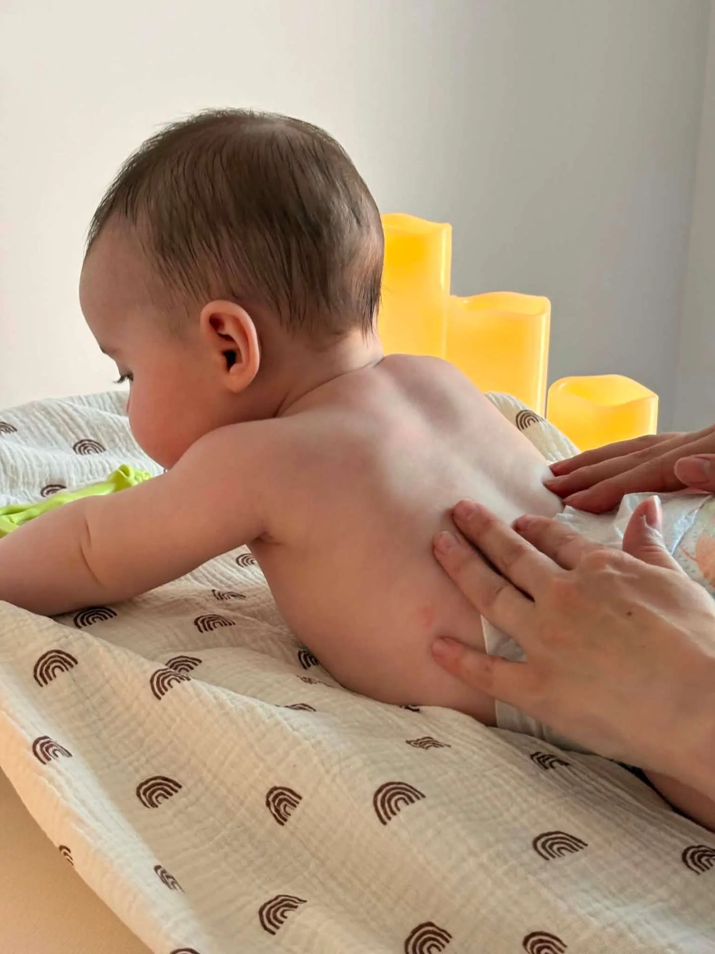 Mains d'une adulte massant délicatement un bébé allongé